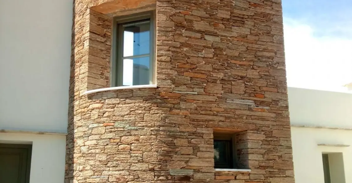 Στρογγυλός πέτρινος πύργος με δύο παράθυρα, δίπλα σε ασβεστωμένο σπίτι